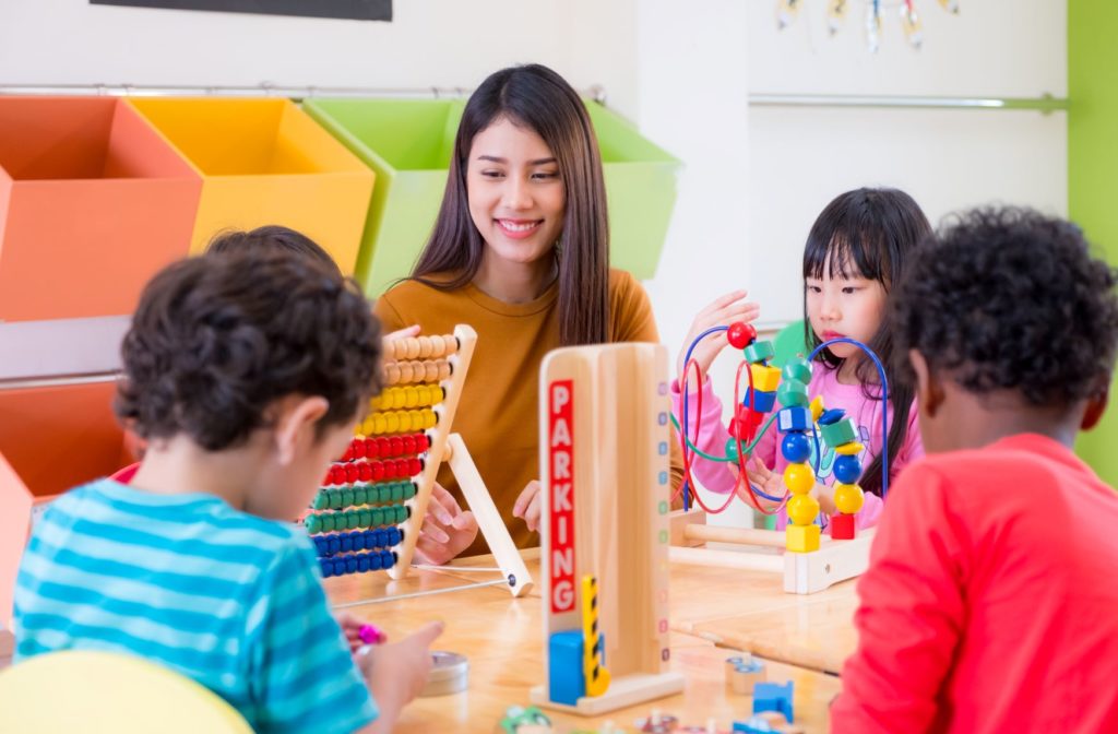 daycare teacher supervises three children playing with toys
