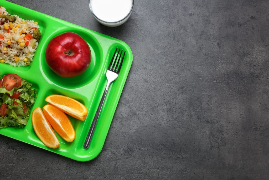 an apple, orange slices, salad, and rice all placed in separate compartments of a food tray