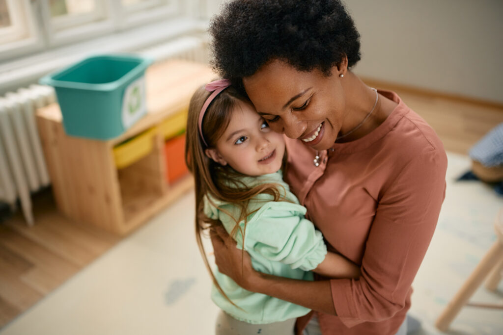 Teacher comforts young girl with a hug.