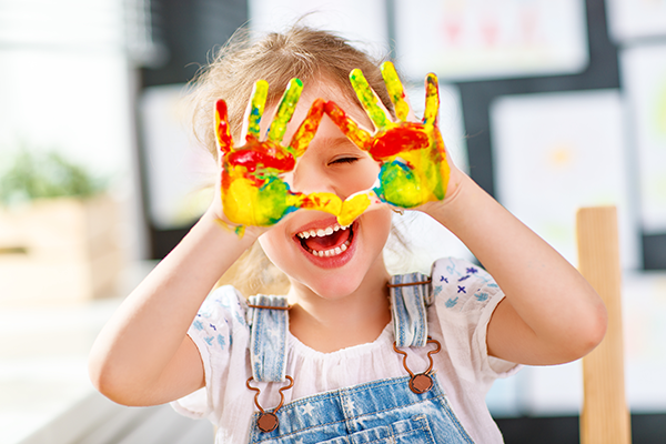 child holds up paint-covered hands