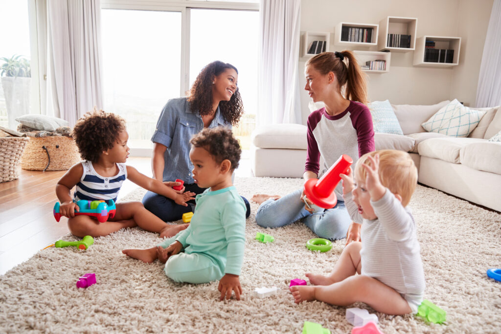 Moms talk to each other during a playdate with their toddlers.