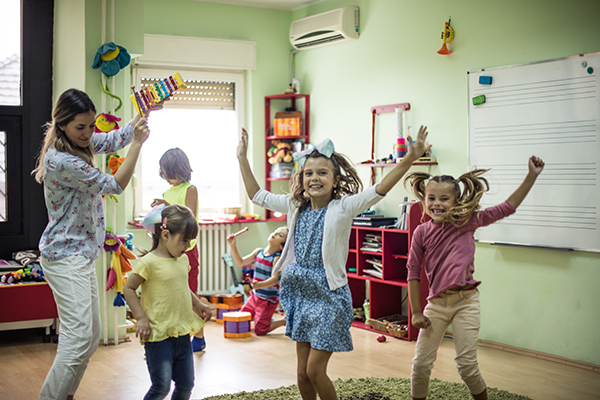 a daycare teacher dances with her students in the classroom