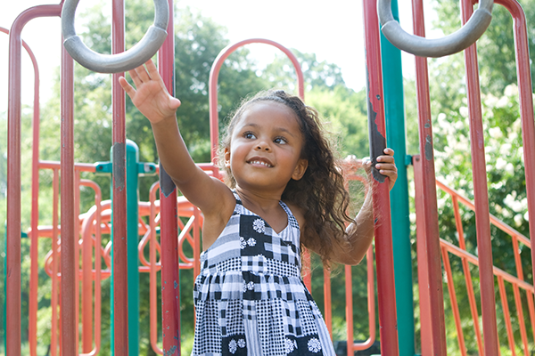 Young girl plays outside on playground equipment.