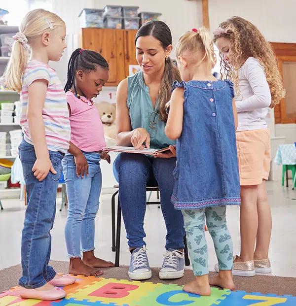 Preschool teacher explains sight words to children with a book.