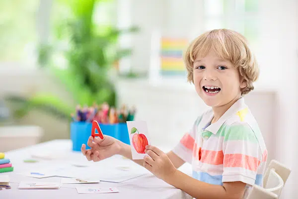 Young boy learns sight words using flashcards and an apple.