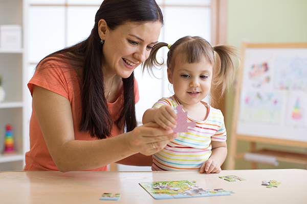 Teacher helps a child complete a puzzle.