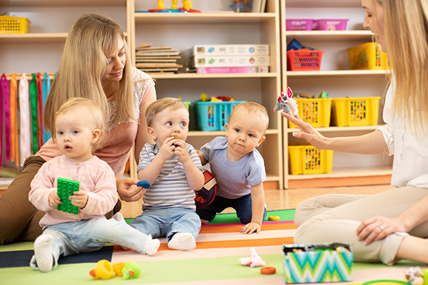 Teachers in a daycare play with infants.