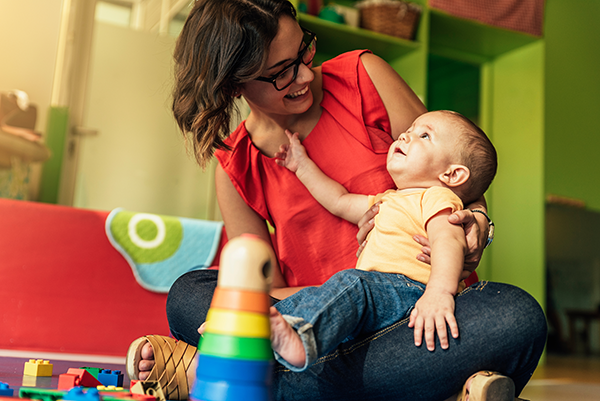 Daycare teacher plays with a baby.