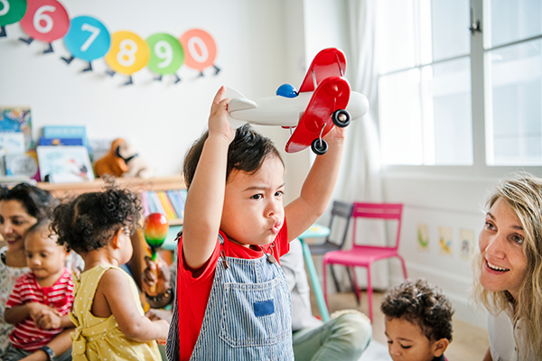 Preschool boy plays with toy airplane.