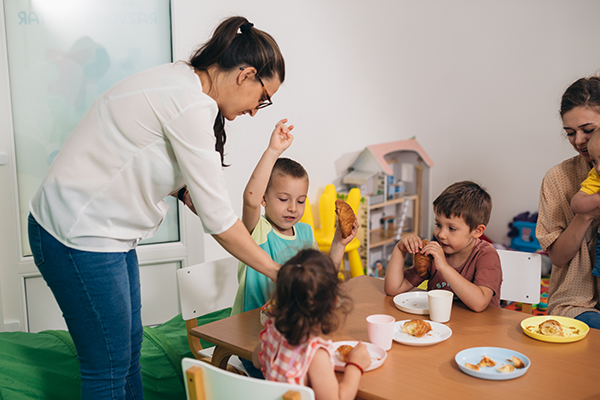 Teacher serves breakfast to children in a daycare.