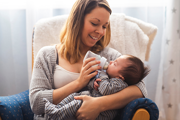 Woman feeds a bottle to a baby.