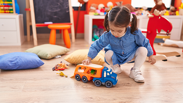 Preschool girl plays with a toy truck.