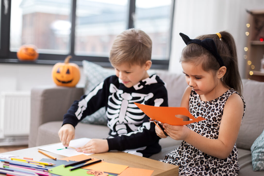 Two preschool children cut out pumpkins as part of craft time.