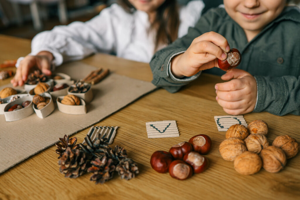 Preschool students make a craft using acorns.